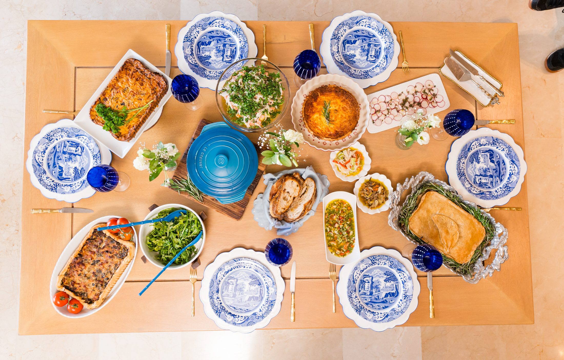Mesa servida con tartas, dips y platos de Homemade sobre vajilla azul
